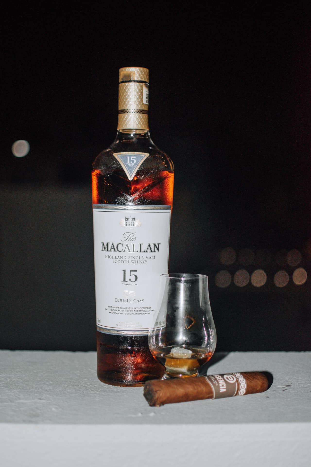 Botella de whisky y copa en ambiente nocturno
